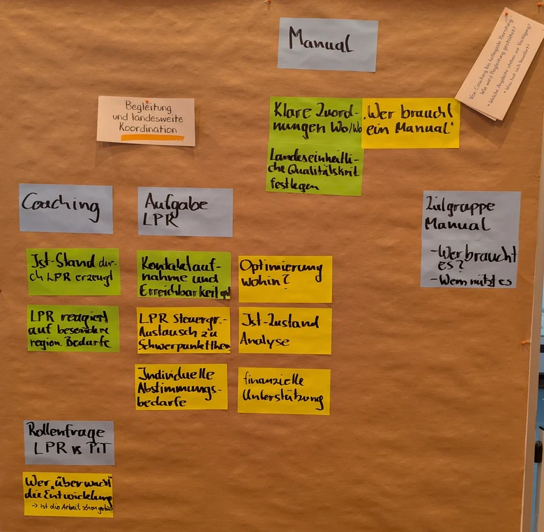 An einer Pinnwand hängen bunte Karten als Antwort auf die Frage nach Begleitung und landesweiten Koordination im Rahmen von PiT.