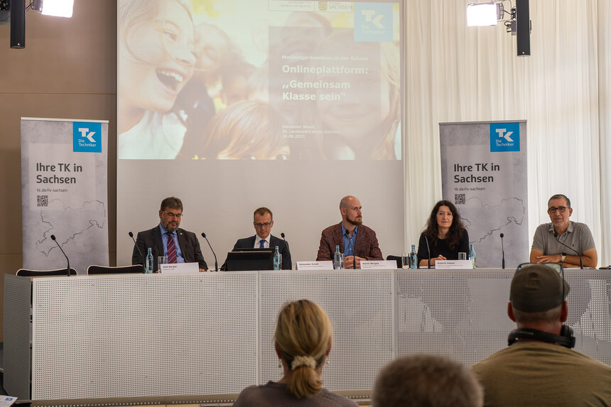 Fünf Personen an einem Tisch während einer Pressekonferenz