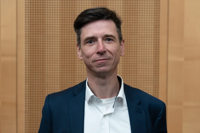 Portrait von Matthias Böhme vor einer hellbraunen Holzwand