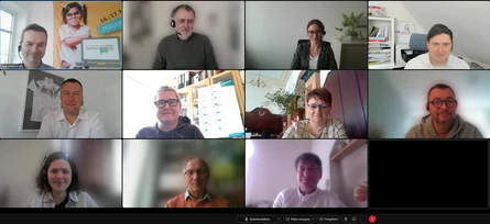 Im Ausschnitt einer Videokonferenz sind elf Kacheln mit Personen zu sehen.
