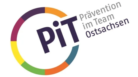 Links ist ein Kreis mit bunten Umrissen. An einer Stelle ist dieser unterbrochen und dort steht "PiT". Neben dem Kreis steht zudem "Prävention im Team" in grauer Schrift und darunter "Ostsachsen" in blauer Schrift.