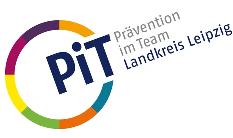 Links ist ein Kreis mit bunten Umrissen. An einer Stelle ist dieser unterbrochen und dort steht "PiT". Neben dem Kreis steht zudem "Prävention im Team" in grauer Schrift und darunter "Landkreis Leipzig" in blauer Schrift.