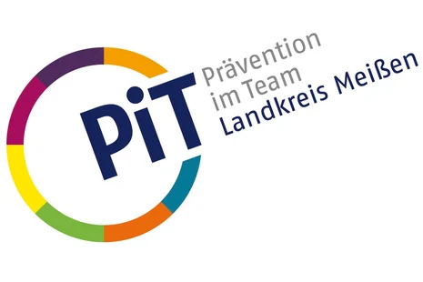 Links ist ein Kreis mit bunten Umrissen. An einer Stelle ist dieser unterbrochen und dort steht "PiT". Neben dem Kreis steht zudem "Prävention im Team" in grauer Schrift und darunter "Landkreis Meißen" in blauer Schrift.