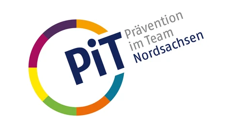 Links ist ein Kreis mit bunten Umrissen. An einer Stelle ist dieser unterbrochen und dort steht "PiT". Neben dem Kreis steht zudem "Prävention im Team" in grauer Schrift und darunter "Nordsachsen" in blauer Schrift.