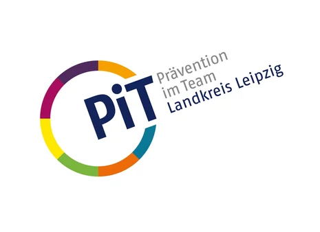 Links ist ein Kreis mit bunten Umrissen. An einer Stelle ist dieser unterbrochen und dort steht "PiT". Neben dem Kreis steht zudem "Prävention im Team" in grauer Schrift und darunter "Landkreis Leipzig" in blauer Schrift.