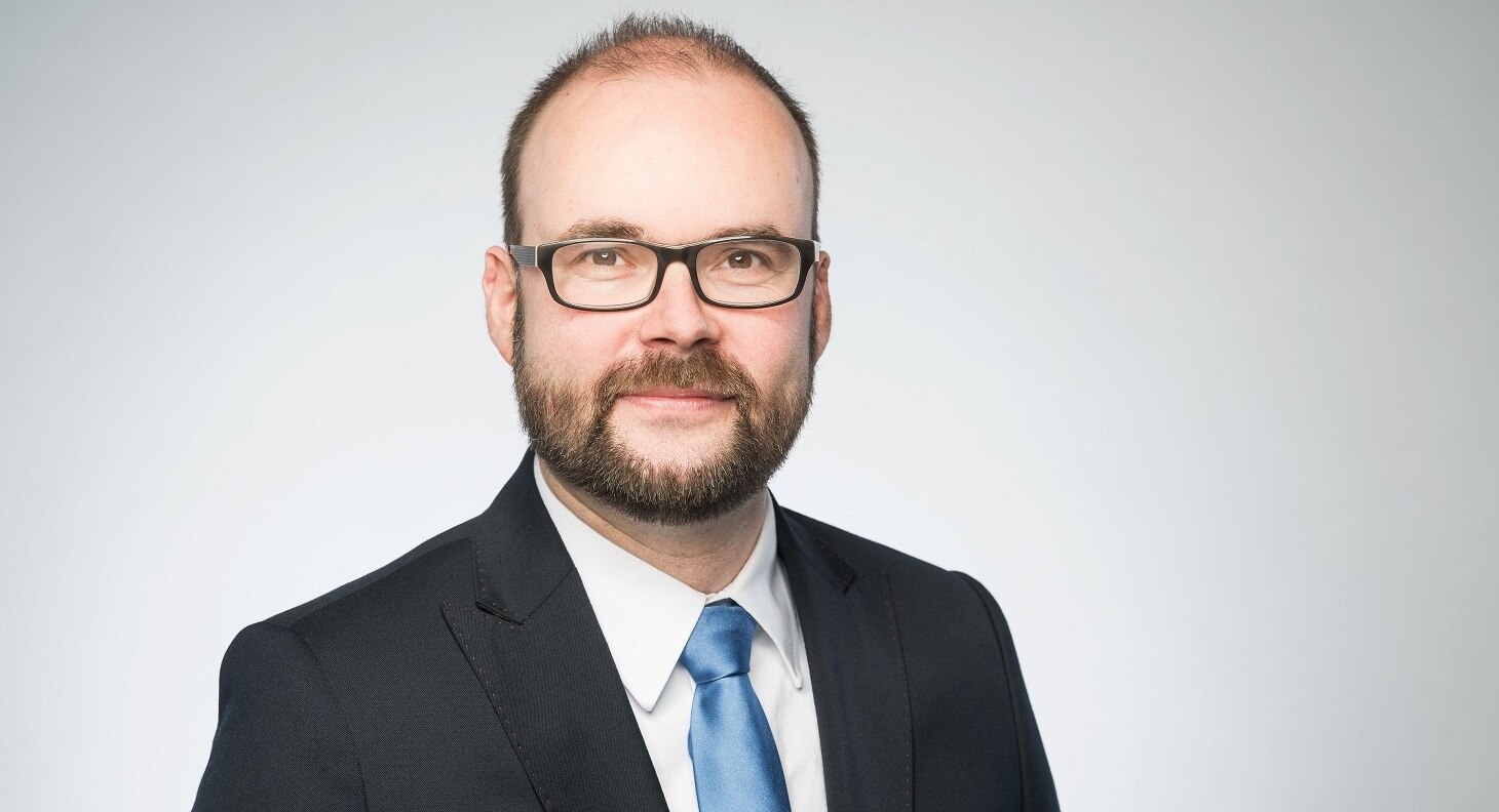 Oberkörperportrait von Staatsminister Christian Piwarz im schwarzen Sakko mit weißem Hemd und blauer Krawatte