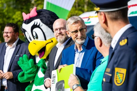 Fünf Männer stehen in einer Reihe. Dazwischen steht noch ein Maskottchen Willi Wachtel.